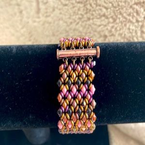 Pink purple and bronze colored woven bracelet